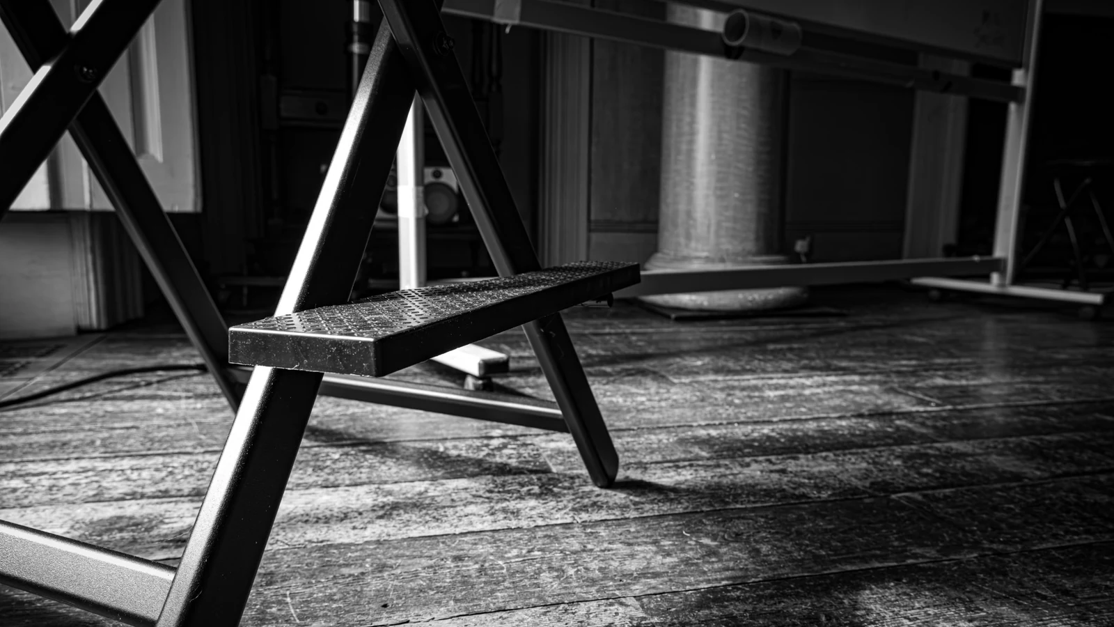 Black and white photograph of a step ladder and wooden floor at the Cohort 005 venue